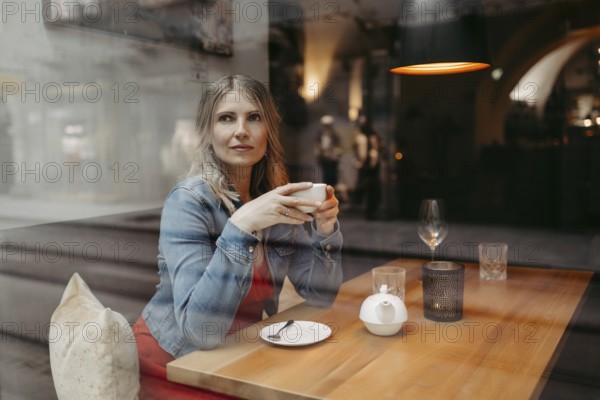 Blonde, attractive woman, 40+, sitting in a coffee house by the window