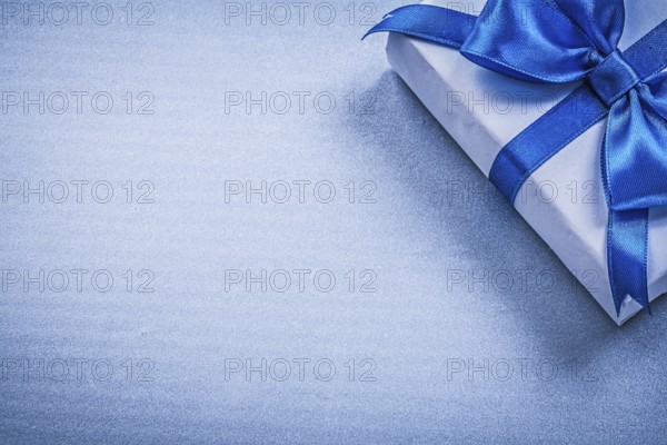 Present box with bow on blue background copyspace holidays concept
