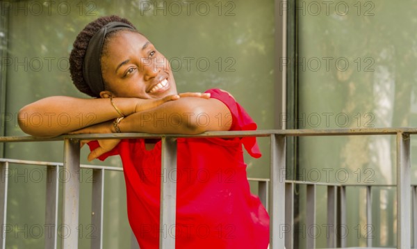Woman leaning on a balcony railing, smiling brightly in natural light, Taken in Daejeon, South Korea