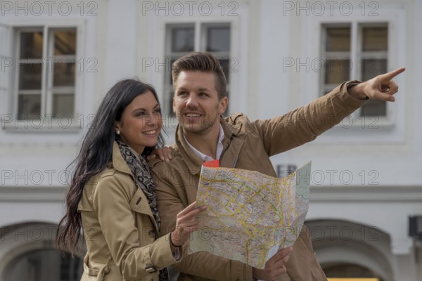 Young couple with city map and travel guide while visiting a city on holiday Austria