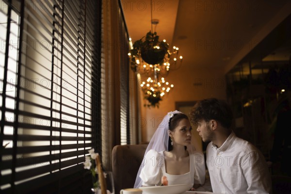Bride and groom share an intimate look in a romantic cafe setting