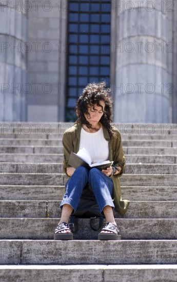 Vertical shot of thoughtful woman sketching on the steps of her college