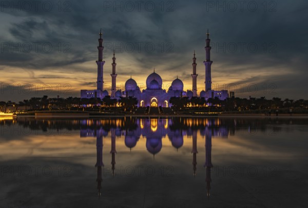 A picture of the Sheikh Zayed Grand Mosque reflected on the Oasis of Dignity pool, at sunset
