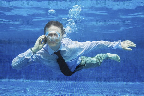 Caucasian businessman talking on a mobile phone underwater