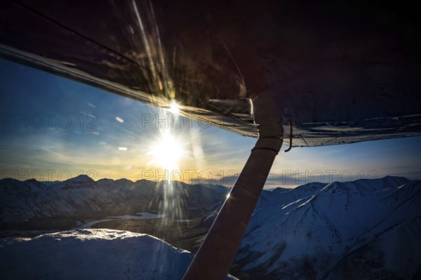 View from an aeroplane of a snow-covered mountain landscape at sunset, Yukon, Canada, Whitehorse