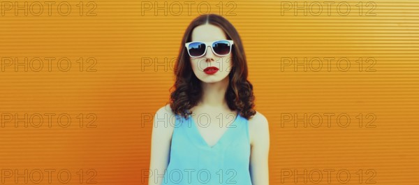 Portrait of young woman posing wearing dress on an orange background