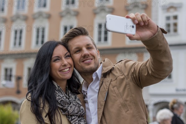 A young couple takes a self-portrait with a mobile phone. Selfies are in. Austria