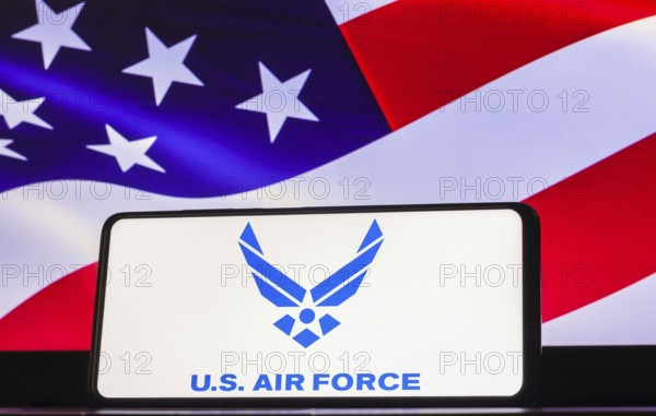 In this photo illustration the United States Air Force (USAF) logo seen displayed on a smartphone screen, United States of America flag in the background