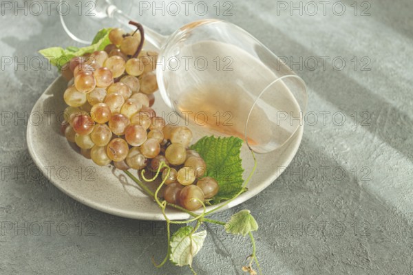 A branch of white grapes, on a gray plate, with a glass of white wine, top view, natural light, food concept, no people