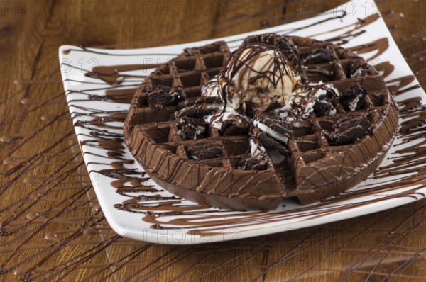 Wafer cake in a square white plate on a wooden lacquered surface with reflection
