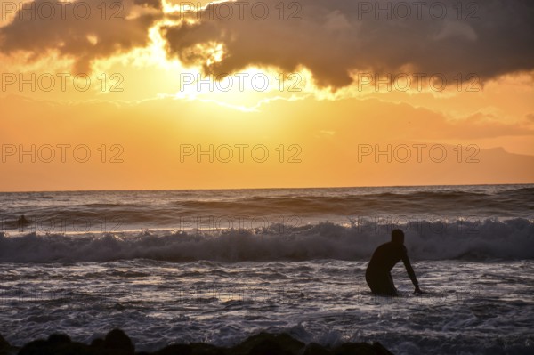 Single surfer at sunset on a calm ocean