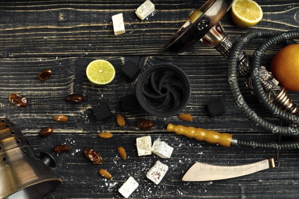 Arabic hookah with a tobacco flavor of a mixture of citruses. Top view of a dark wooden background. Still life. Copy space. Flat lay