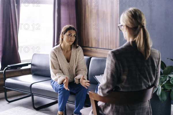 Eine junge Frau spricht in einem Gespräch mit einem professionellen Psychologen über ihre Probleme. Eine moderne Frau entscheidet in einem vertraulichen Gespräch mit einem professionellen Berater, was zu tun ist