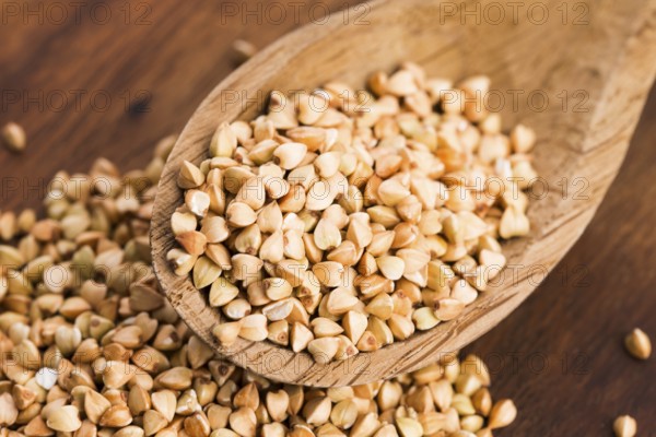 Buckwheat with a spoon on a wooden boards background