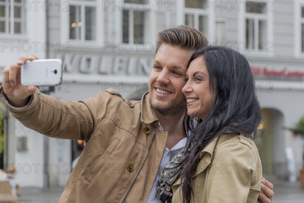 A young couple take a self-portrait with a mobile phone. Selfies are in. Austria