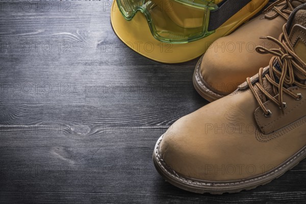 Protective spectacles building helmet safety boots on wooden board