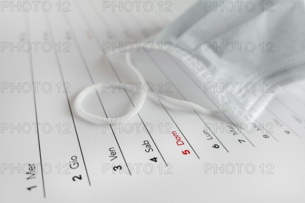 Montly calendar with self protection face mask. Coronavirus concept. Beginning / end of the pandemic. Deadline concept with sheet of monthly calendar. Coronavirus COVID-19. Copy space. Selective focus