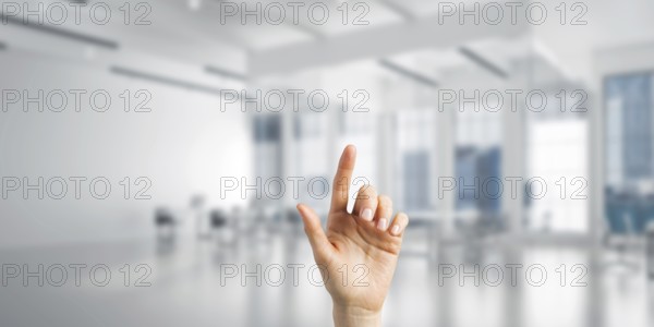 Close of woman hand touching screen with finger and office at background