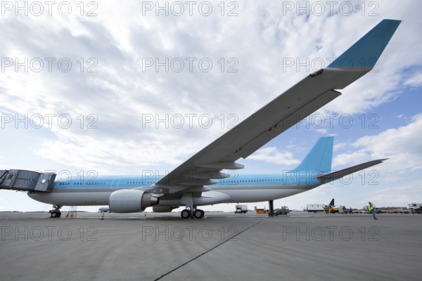 Large blue and white airplane stands at the airfield ready to depart, people&#39, s faces are unrecognizable