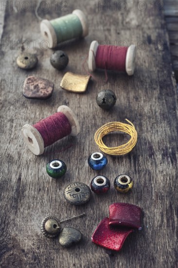 The spool of thread, beads and wire for needlework on wooden background