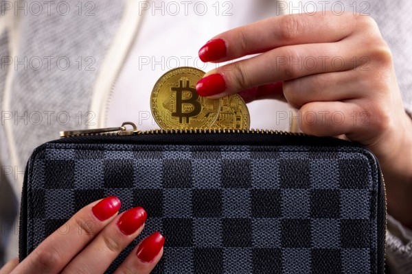 Virtual cryptocurrency money Bitcoin golden coins in the left hand of a woman with red nail polish and a purse. The future of money