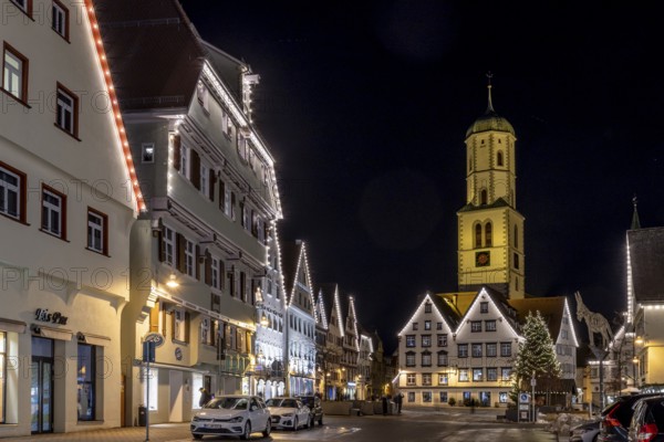Night photo of historic buildings around the market square with Christmas tree and Christmas lights around the roofs of the buildings and in the background the steeple of the parish church of St Martin, Biberach an der Riß, Upper Swabia, Baden-Württemberg, Germany