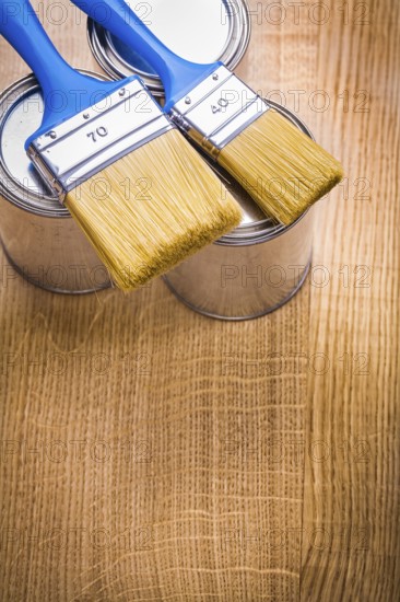 Vertical view organized copyspace two paint brushes on three cans and wooden board