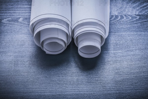 White rolled up blueprints on blue painted board