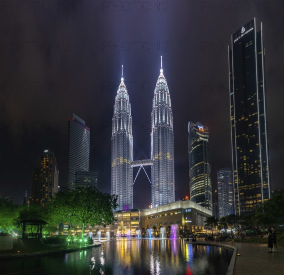 A picture of the Petronas Twin Towers, the KLCC Park water and light fountain show and the Suria KLCC shopping center at night