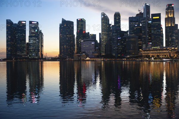 02.12.2020, Singapore, Republic of Singapore, Asia, View over Marina Bay to the illuminated business district with its modern skyscrapers in the evening light during the global corona pandemic