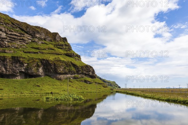 Usual summer in Iceland. Smooth water of the cold lake reflects clouds