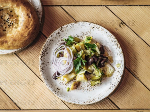 Authentic shot of georgian style salad with red beans, potatoes, salted cucumber on rustic wooden tabletop