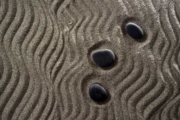 Drawings on light gray sand and black stones in a small Zen garden