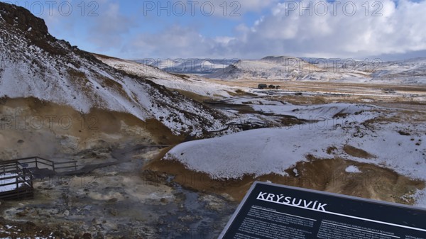 Seltún, Krýsuvík, Iceland, 03-23-2021: View over geothermal area Seltún, part of volcanic system Krýsuvík, with steaming hot springs, fumaroles and information board on cloudy winter day