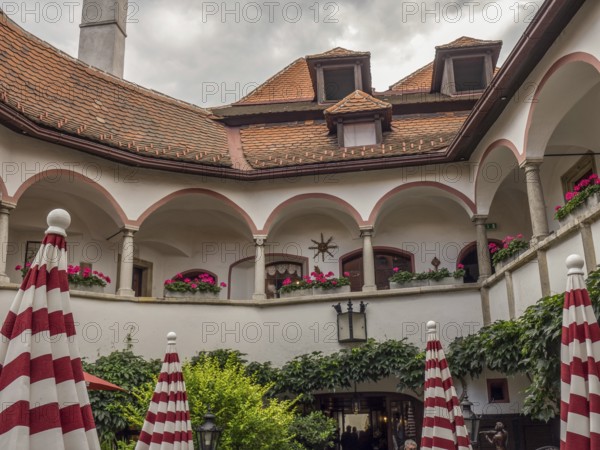 Historic courtyard with arcades, balconies, red and white umbrellas and many plants, Dürnstein, Wachau, Danube, Austria
