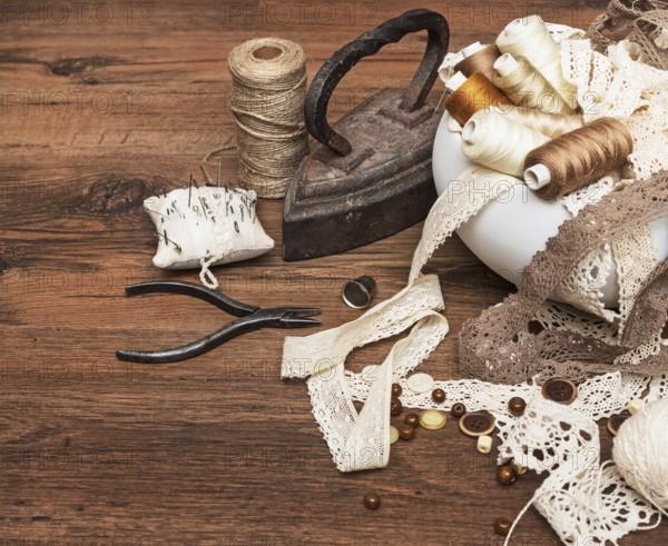 Sewing concept. Old flatiron, thread spools, buttons and sewing needles