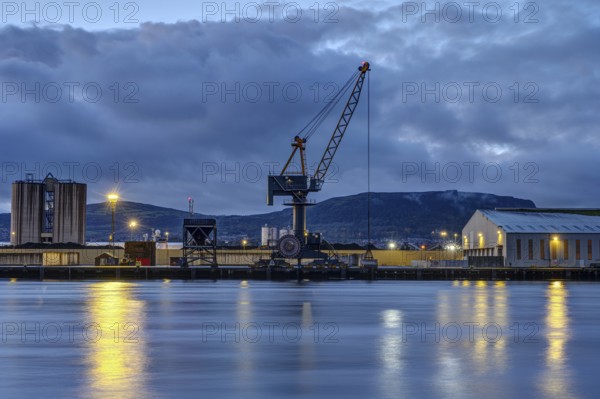 A loading crane and warehouses in Belfast harbour at dusk
