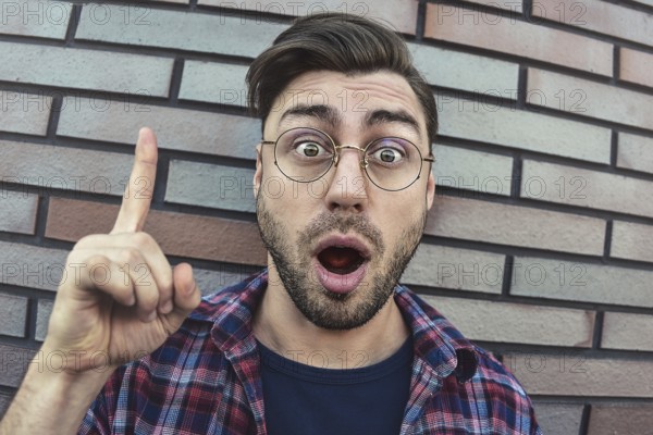 Great idea! Handsome man keeping finger pointed upwards, showing something above his head, making gesture with index finger. Eureka, solution sign concept