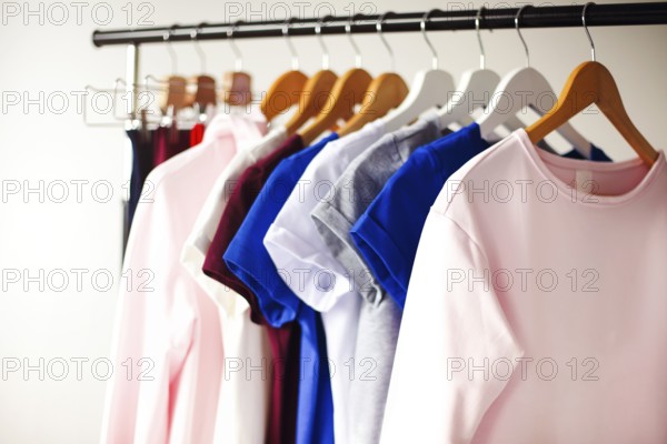 Rack with various feminine shirts placed in minimalist style room with white walls
