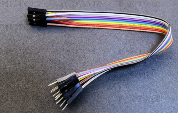 Rainbow jumper wires with pin connectors placed on a blue-toned surface