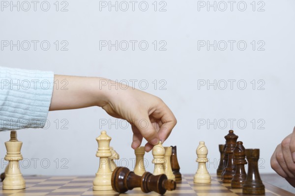 Close-up of a child's hands playing chess with a white background and copy space