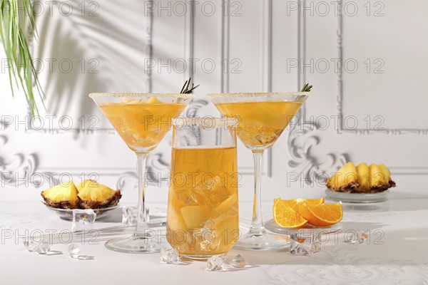 Summer party concept. Lemonade royal cocktail, martini or punch made of tequila, rum and vodka with pineapple slices, orange, ice and rosemary. Diet drink for bar or cafe advertising, restaurant menu