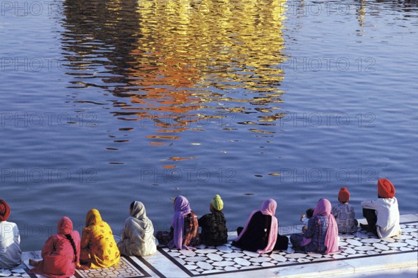 Pilgrims sitting near pond of golden temple, amritsar, punjab, india, asia