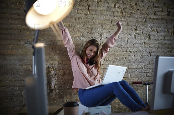 Excited happy young woman at office open arms with laptop