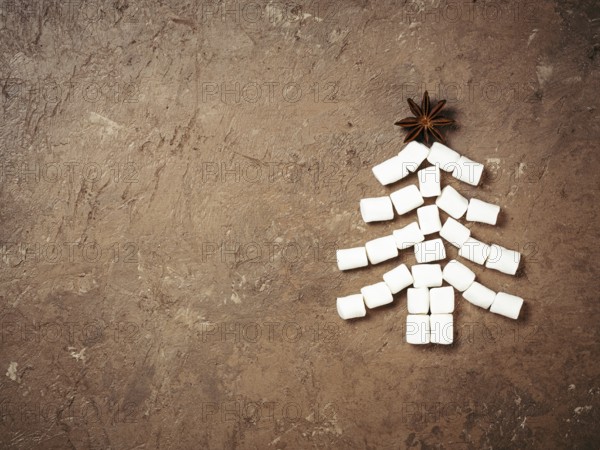 Christmas food and drink background. Christmas tree made from marshmallow and star anise on brown concrete textured background, Holiday and new year concept. Copy space. Top view or flat lay