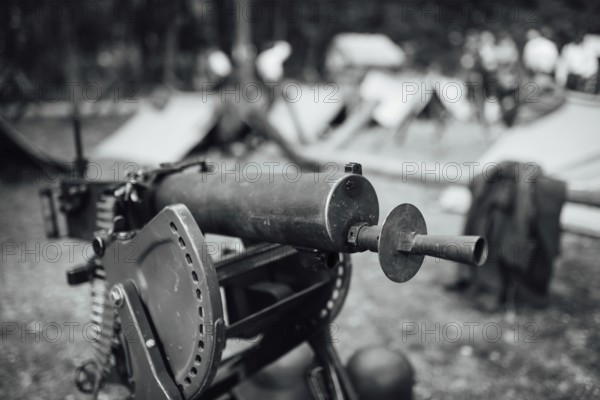 A heavy machine gun from I Word War with a military camp in the background