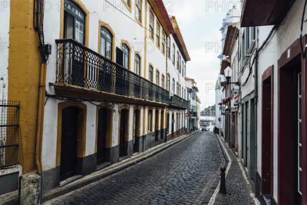 Angra do Heroismo, Portugal, July 1, 2022: Street with Traditional colonial houses painted in vibrant colors in the old town. Terceira Island, Azores