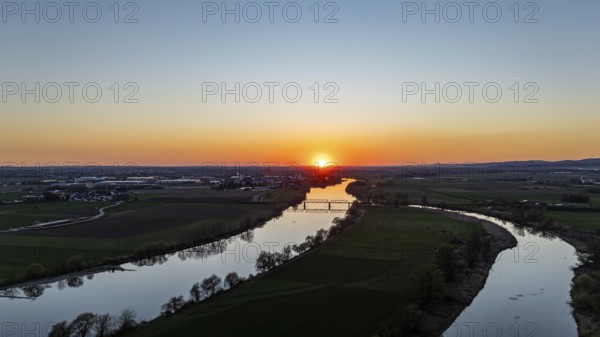 River (Danube) in the foreground with setting sun on the horizon, surrounded by fields, wide and calm atmosphere, Bogen, Lower Bavaria, drone shot