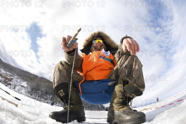 UST-BARGUZIN, RUSSIA - APRIL 11: A fisher sits with a rod at an ice hole during the 5th Annual Baikal Fishing, April 11, 2009 in Ust-Barguzin, Buryatia, Russia