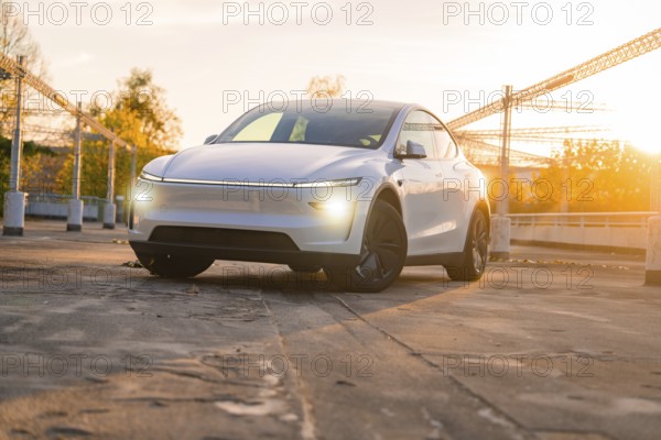 Perspective on a white car at sunset in a city car park, Tesla new Model Y Juniper, Nagold, Germany